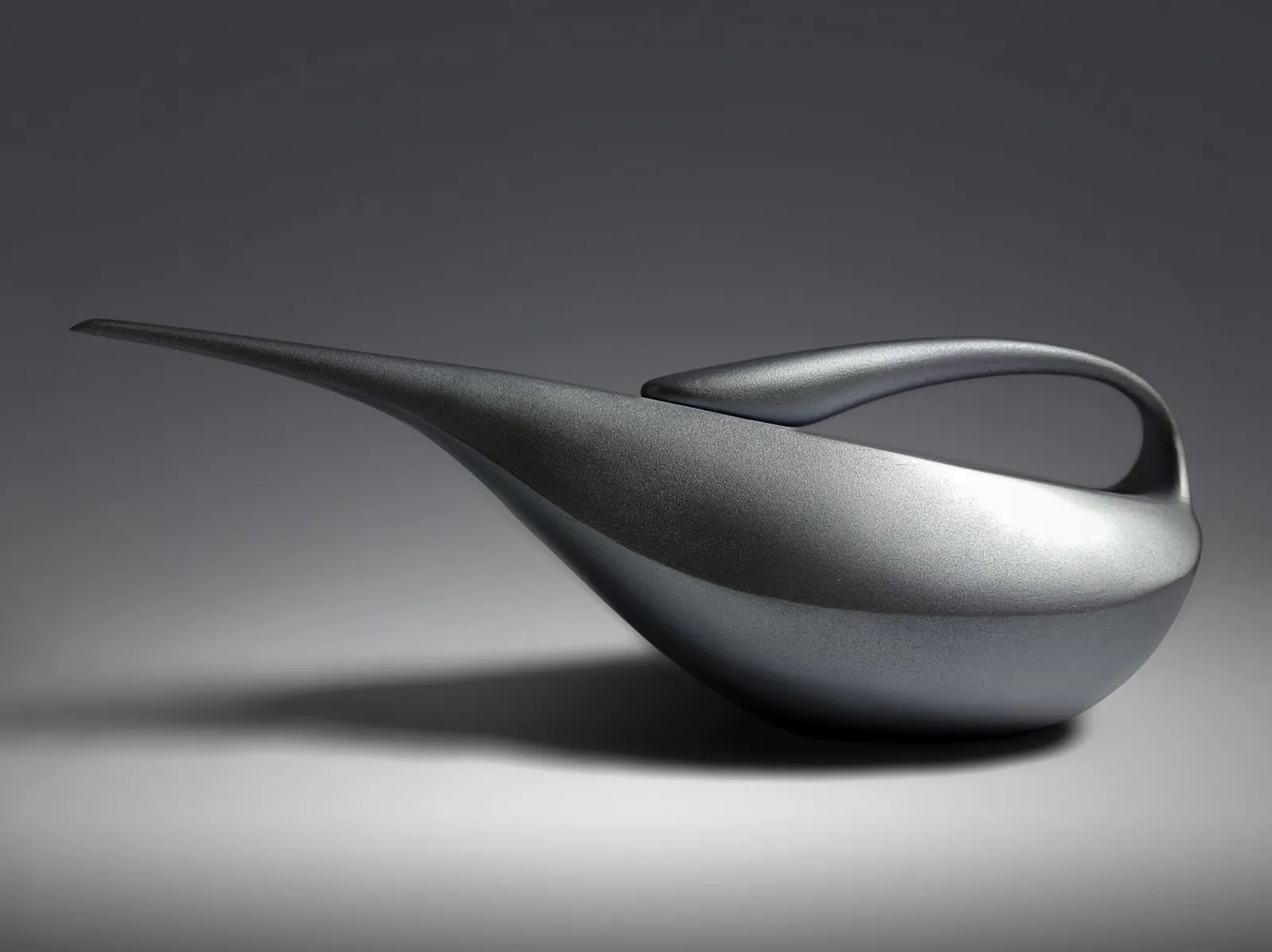 Silver sculptural form study with a swept handle