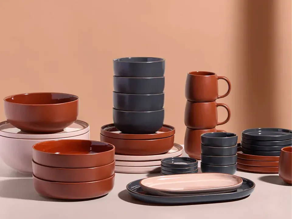 Our Place tableware in terracotta, charcoal and blush: stacked bowls, plates, mugs and a serving platter