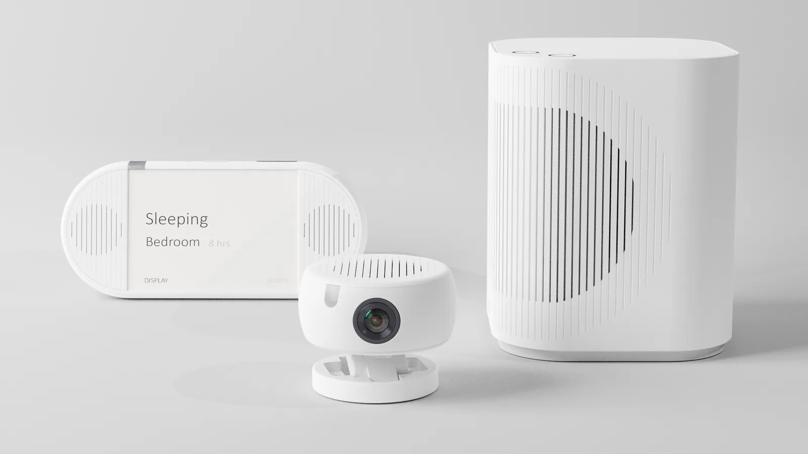 The three LumiMate devices on a grey surface: the caregiver display reading Sleeping, Bedroom, 8 hrs, a small sensor unit with a camera lens, and the taller hub with a curved speaker grille