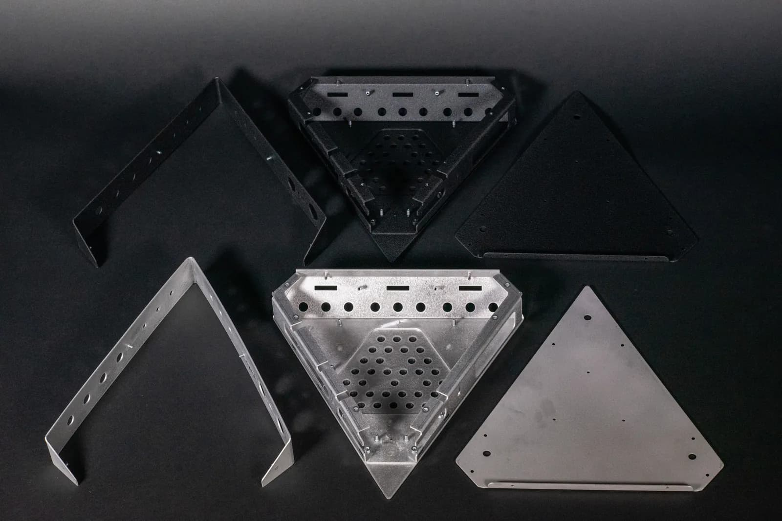 Flat sheet metal parts in black and raw aluminium, laid out before bending