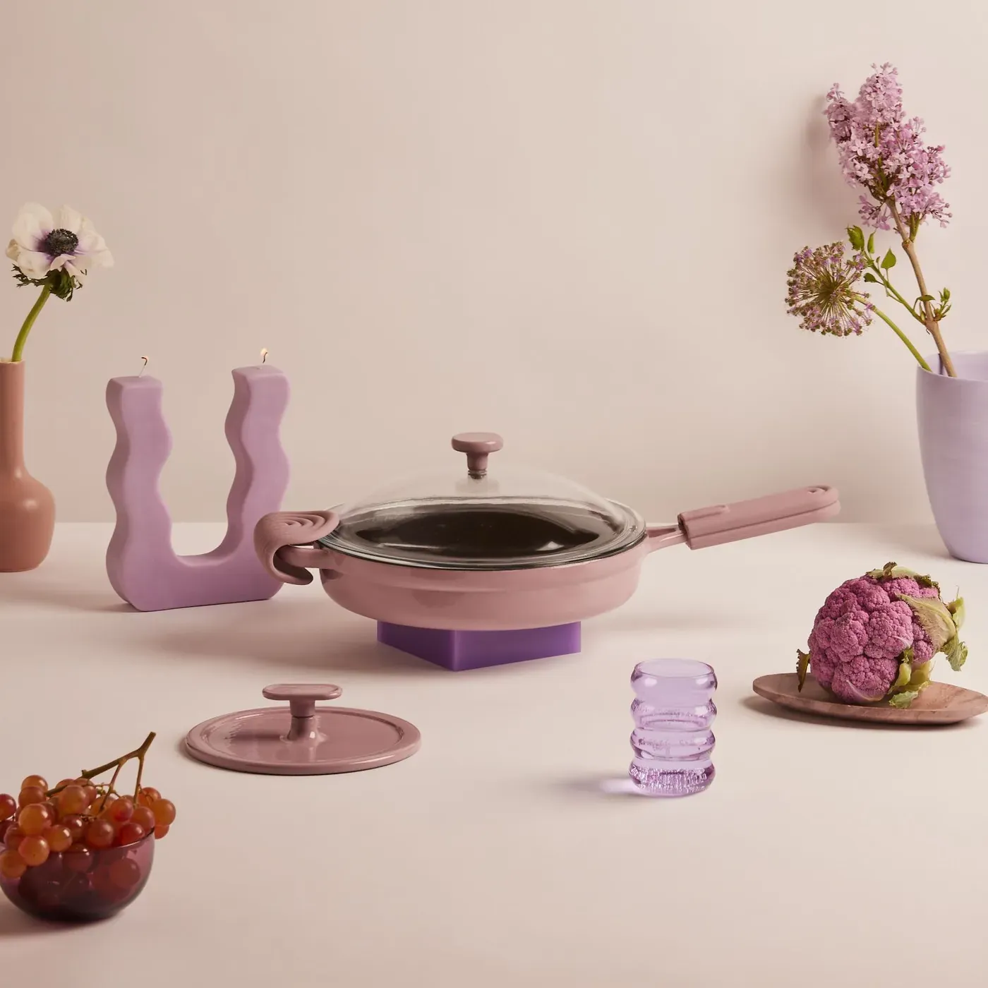 Lilac cast iron pan with a glass lid, styled with flowers and fruit