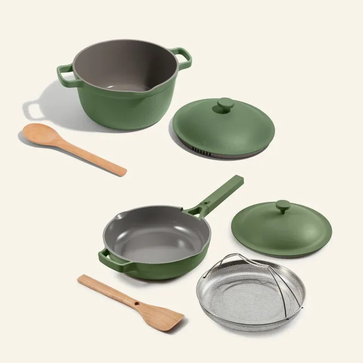 Flat lay of the sage Always Pan and Perfect Pot with lids, steamer basket, spoon, and spatula