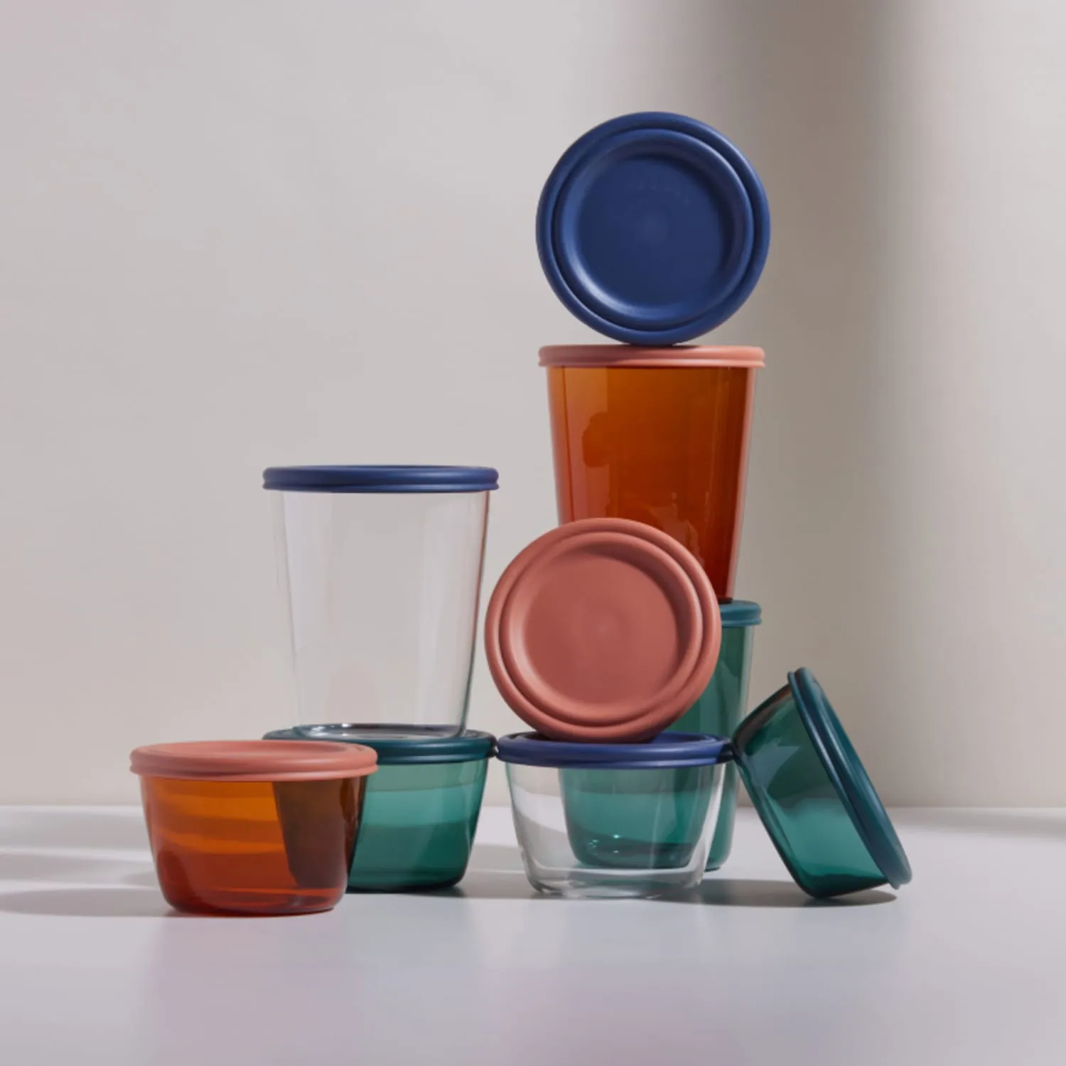 Stacked glass storage containers with blue, terracotta, and teal lids