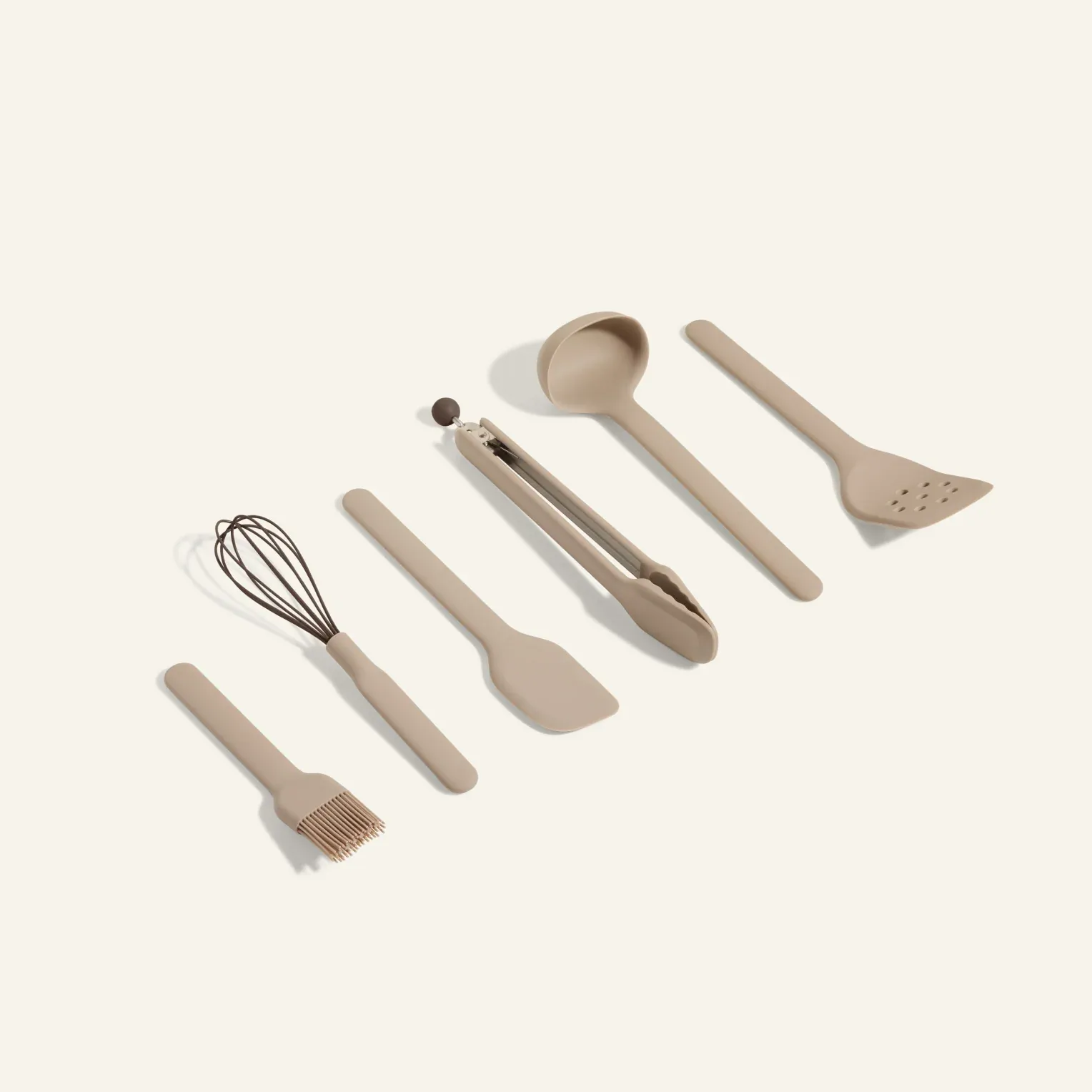Set of beige silicone utensils laid out in a diagonal row