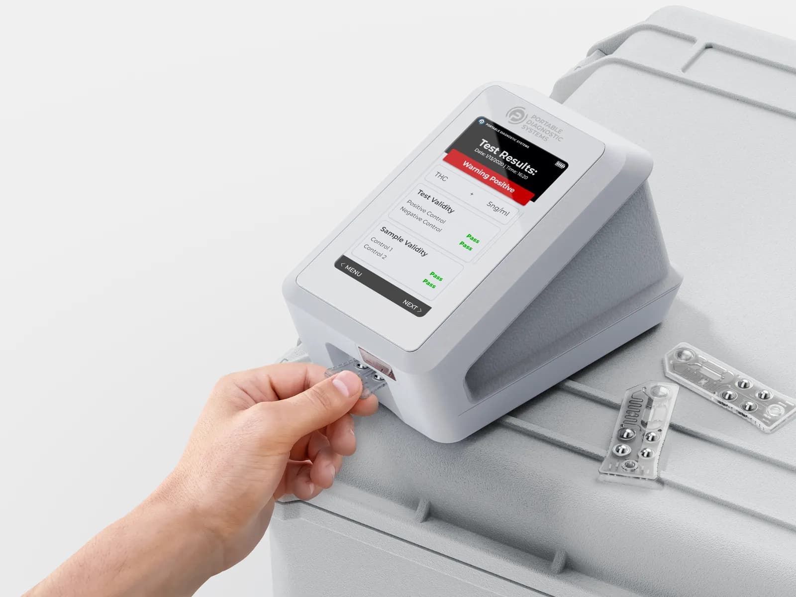 A hand sliding a cartridge into the slot at the front of the white Integrity-1, which sits on a grey field case