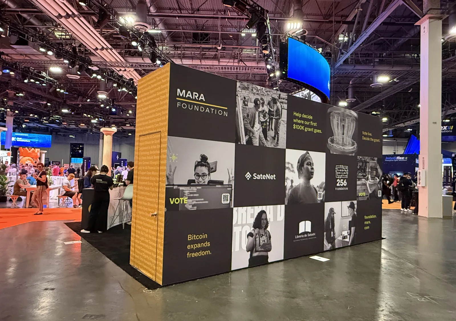 The MARA Foundation booth: a gold patterned corner and a dark wall of black and white portraits with vote prompts