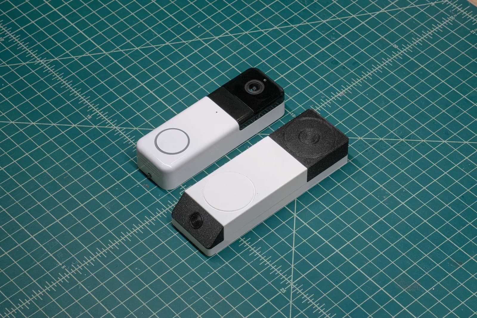 The assembled 3D print next to WYZE's existing doorbell on a cutting mat